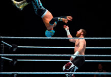 Two wrestlers mid-match, one performing an aerial move.